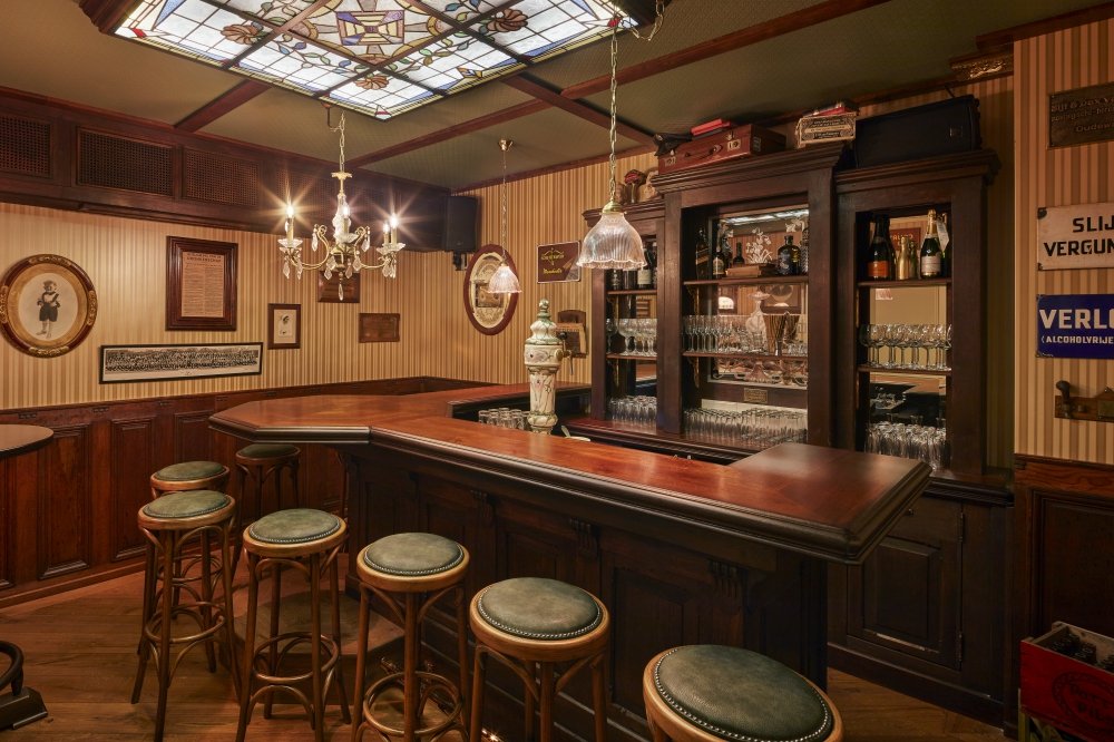 Bar met achterkast, krukken en glas-in-lood plafond.