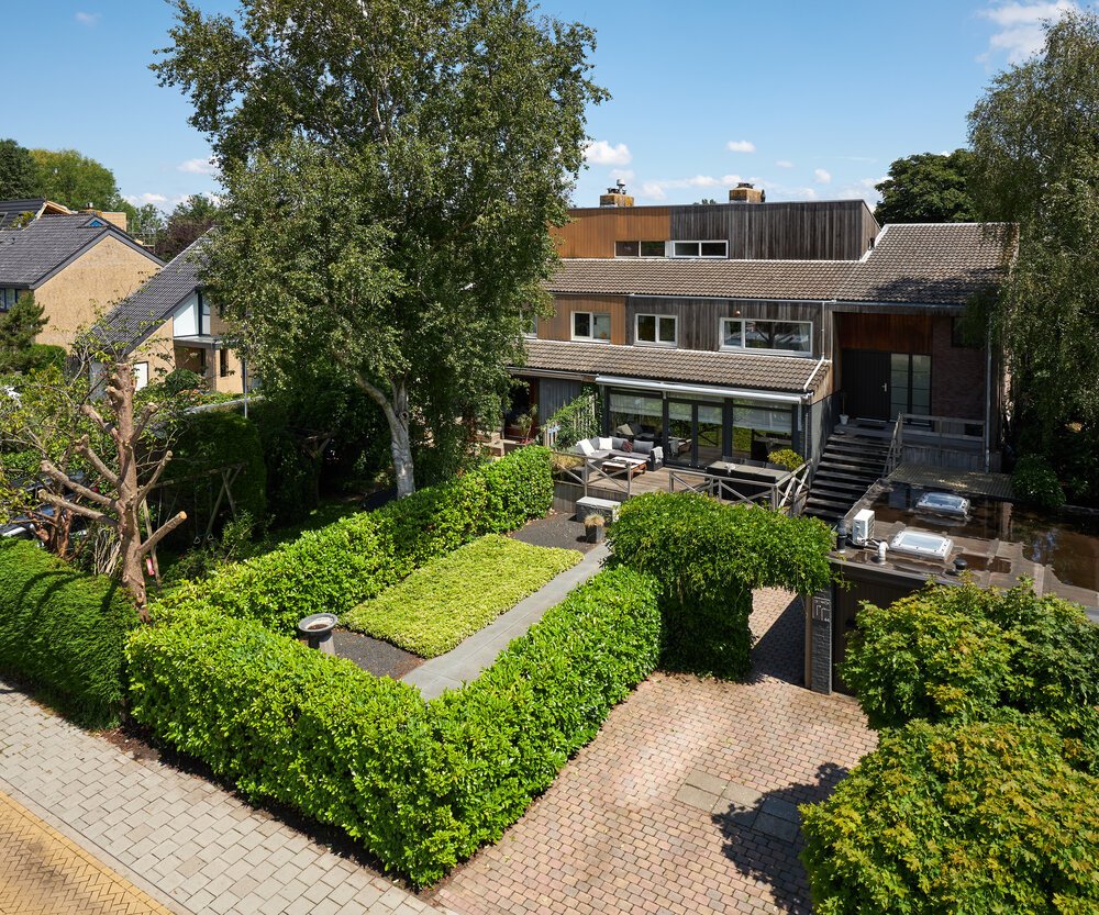 A deep front garden revealed from above, rising beyond the hedge