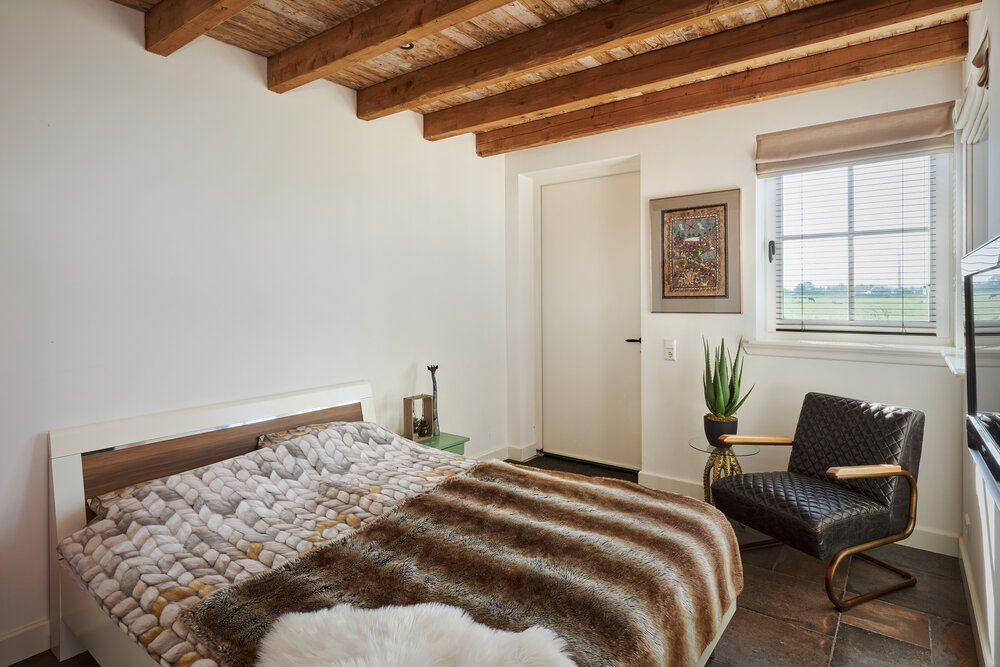 Bedroom with classic windows, a wooden ceiling, and a door opening onto the rear garden.