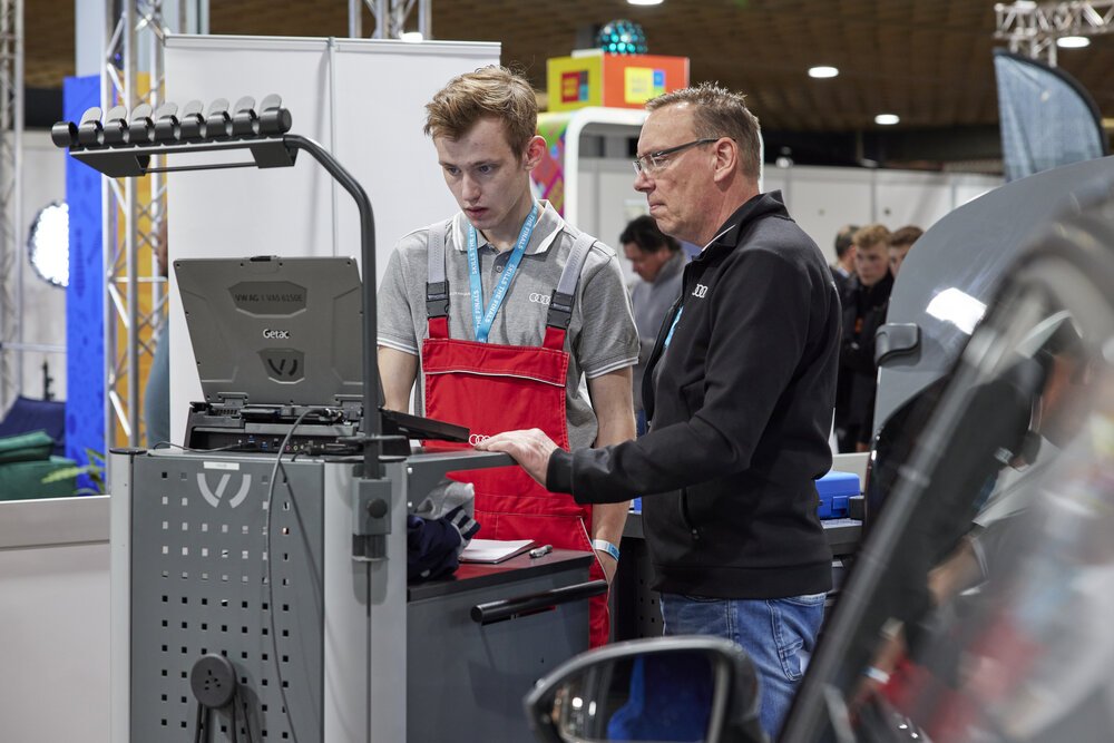 A dealership employee guiding a finalist through a diagnosis.