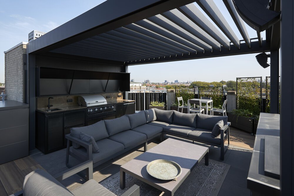 Rooftop terrace with outdoor kitchen, fireplace, and sun shading.