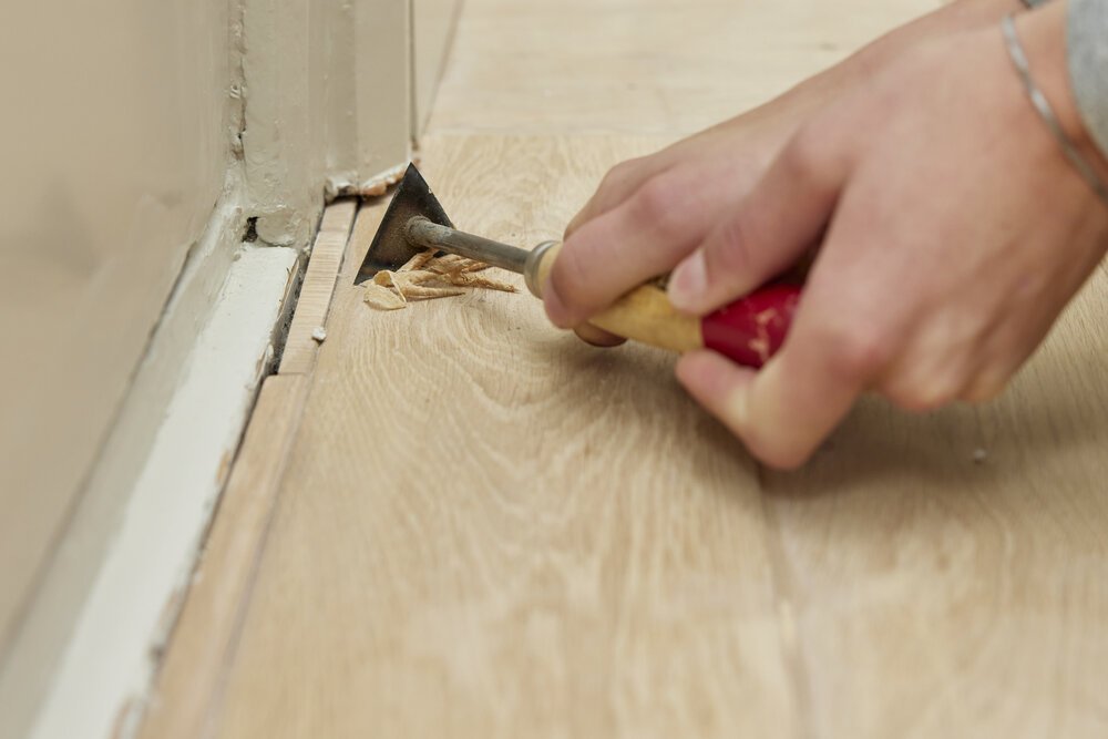 Any stubborn (adhesive) residue is scraped from the oak using a scraper.
