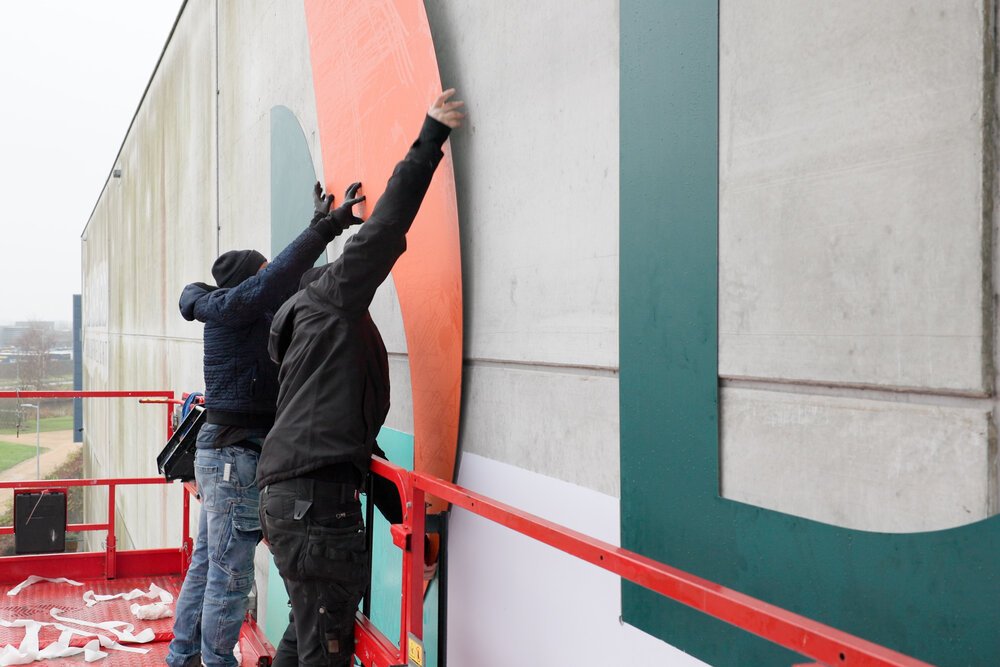 Placing the large new logo on the facade of the Dutch Qargo Warehouse.