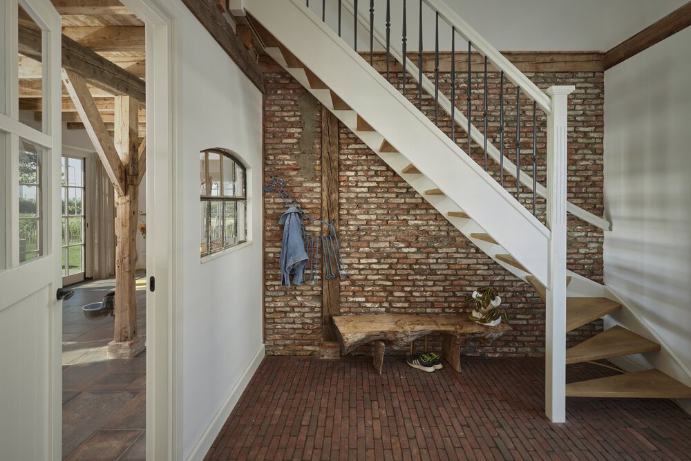 Hergebruikte materialen: de gemetselde muur en getegelde vloer. Deze materialen en elementen als de voerbak in de woonkamer creeëren de sfeer van een boerderijwoning.