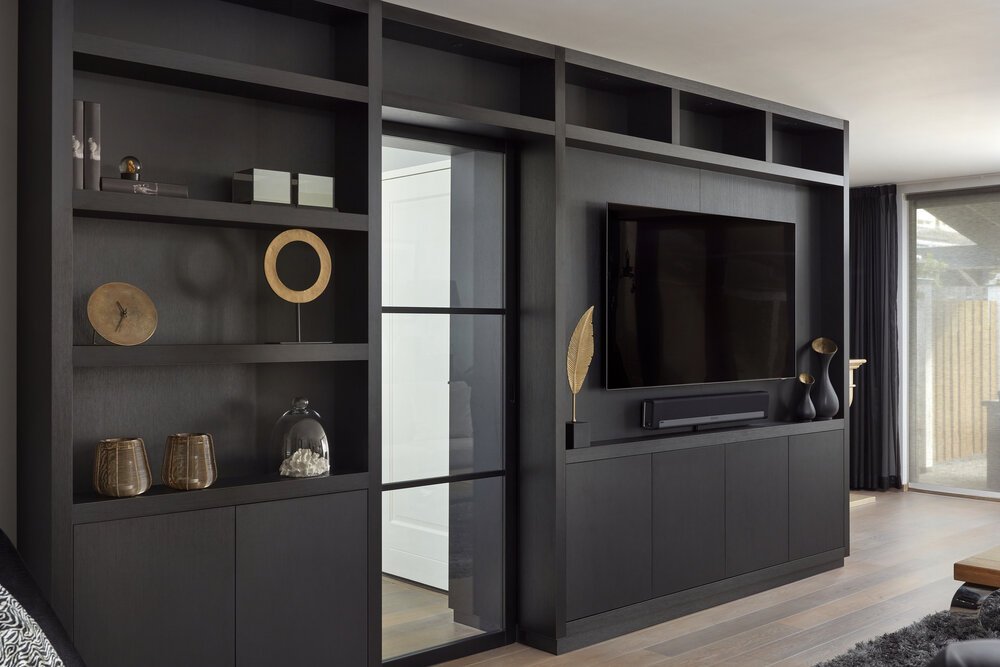 Wandmeubel tegen voormalige buitenmuur creëert interessante indeling woonkamer.